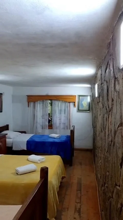 Habitación con dos camas y pared de piedra
