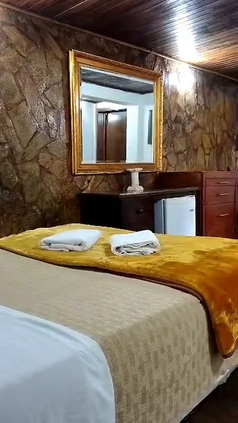 Cama matrimonial con toallas junto a la pared de piedra