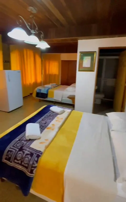 Habitación amplia con techo de madera y nevera