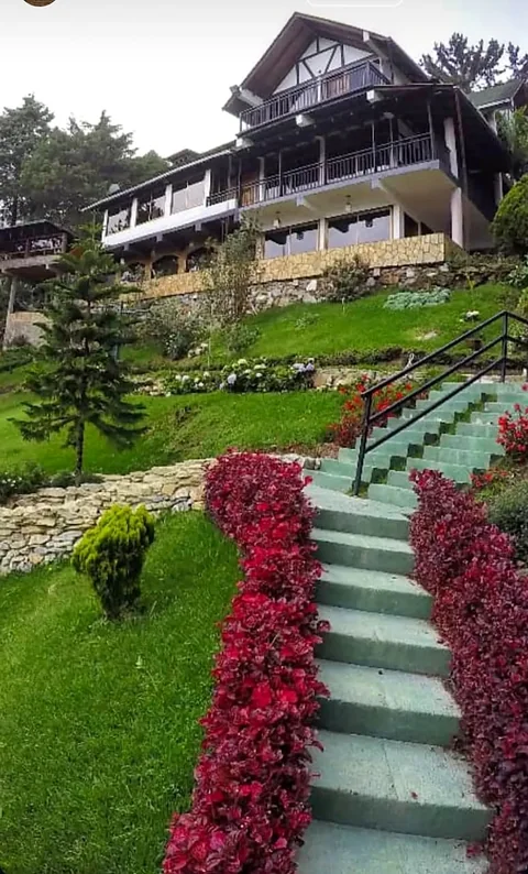 Escalera con flores rojas que sube al chalet entre jardines